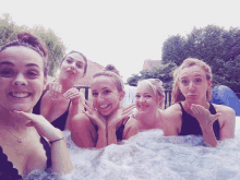 a group of women are posing in a hot tub