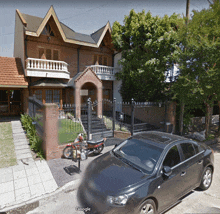 a black car is parked in front of a brick building with a google logo on the bottom right