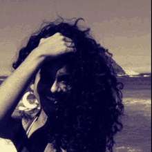 a woman with curly hair holds her hand to her head in a black and white photo