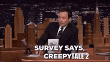 a man in a suit and tie is talking into a microphone and says survey says creepy tall 2 .