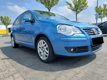 a blue volkswagen is parked on a brick driveway