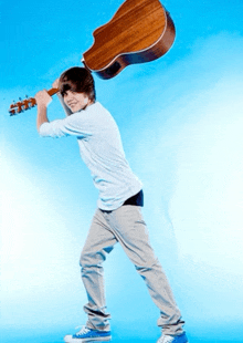 a young man is holding a guitar over his shoulder