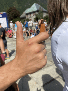 a person giving a thumbs up sign with a crowd in the background