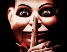 a close up of a puppet holding a finger to his lips