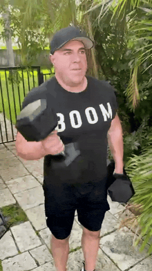 a man wearing a boom t-shirt is holding a dumbbell