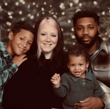 a family posing for a picture with two boys and a baby in front of a christmas tree