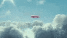 a pink school bus is flying through the clouds in the sky .