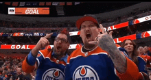 two men in edmonton oilers jerseys celebrate a goal during a hockey game