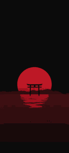 a torii gate is silhouetted against a red sun setting over a body of water .