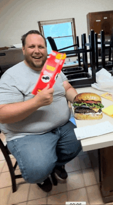 a man is sitting at a table holding a bag of pringles chips