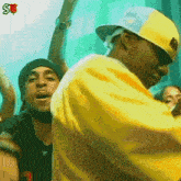 a man wearing a yellow shirt and a hat with the letter s on the front