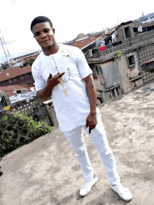 a man in a white shirt and white pants is standing on a roof