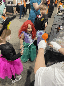 a little girl in a little mermaid costume holds a bubble wand