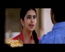 a woman in a pink shirt is talking to a man in a blue shirt with the words ' telugu ' on the bottom