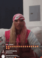 a woman wearing a pink jacket and a red and white scarf is sitting on a couch