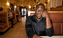 a man in a black shirt sits in a booth in a restaurant