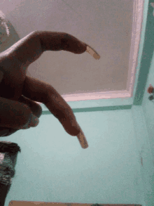 a person 's hand with very long nails reaching up towards the ceiling