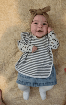 a baby wearing a bib and a denim skirt is smiling