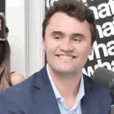a man in a suit is smiling into a microphone .