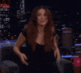 a woman in a black dress is sitting on a couch with her hands on her face
