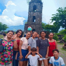 a group of people posing for a picture in front of a stone tower .