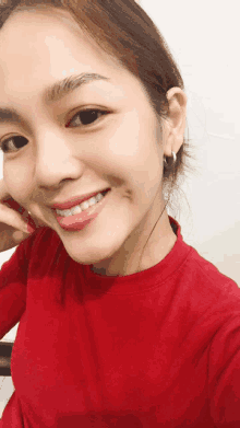 a woman wearing a red shirt is smiling and taking a selfie