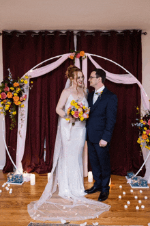 a bride and groom are posing for a photo in front of a floral arch