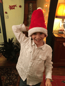 a boy wearing a santa hat stands in front of a sign that says joyeux noël