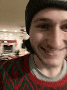 a young man wearing a beanie and a sweater is smiling .