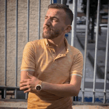 a man wearing a yellow polo shirt and a gold watch