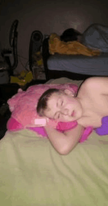 a young boy is sleeping on a bed with a stuffed animal on his head .