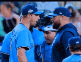 a group of baseball players are standing next to each other and talking .