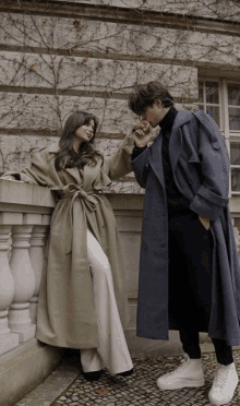 a man and a woman standing next to each other on a balcony