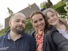 a man wearing a tommy hilfiger shirt poses for a picture with his wife and daughter