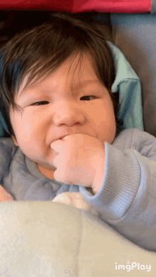 a baby with a tear coming out of his eye is sitting in a stroller with a blue sweater on