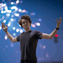 a young man stands with his arms outstretched in front of fireworks