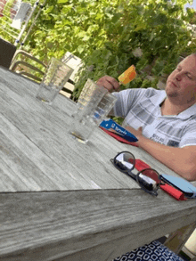 a man is sitting at a table eating a popsicle and reading a book with the number 12 on it