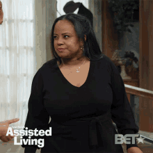 a woman in a black dress is standing in front of a window with the words assisted living on it