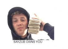 a man in a hoodie is holding a pile of money in his hand .