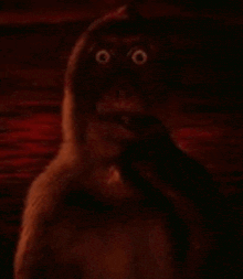 a close up of a monkey scratching its face in front of a body of water