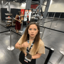 a woman with a lanyard around her neck stands in front of a coca cola machine