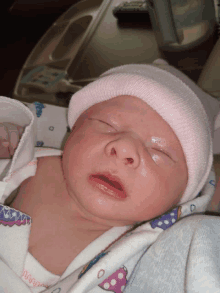 a newborn baby wearing a pink hat and a blanket that says wing