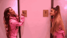 ariana grande and nicki minaj are standing next to each other in a bathroom .