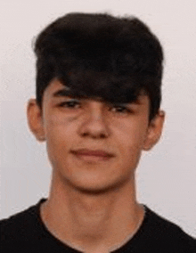 a close up of a young man 's face with a black shirt on .