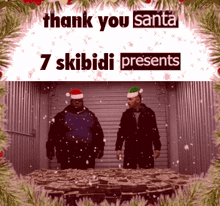 two men wearing santa hats are standing in front of a table full of presents