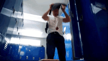 a man is standing in a locker room with blue lockers