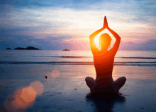 a woman sits in a yoga pose on the beach with the sun behind her