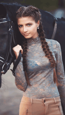 a woman with braids standing next to a horse