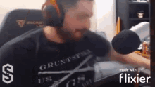 a man wearing headphones and a t-shirt is talking into a microphone while sitting in a chair .