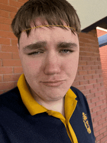 a young man wearing a blue shirt with a yellow collar has a yellow headband around his head